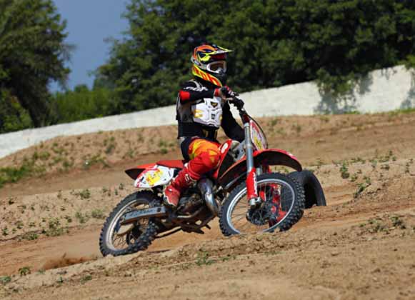 A motocross rider on a red bike on an offroad course