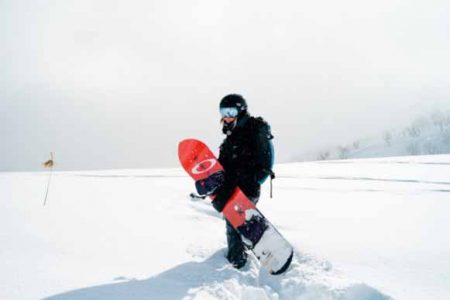 A person wearing snowboarding gear holding a snowboard
